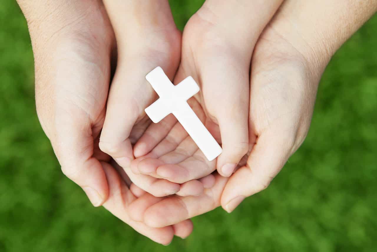 A family holding a cross together