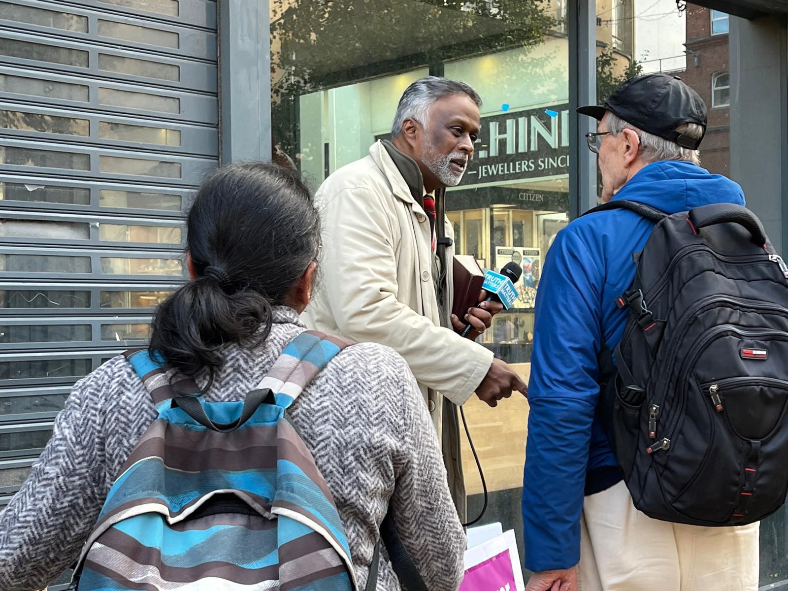 A man with a microphone speaking to people in the street