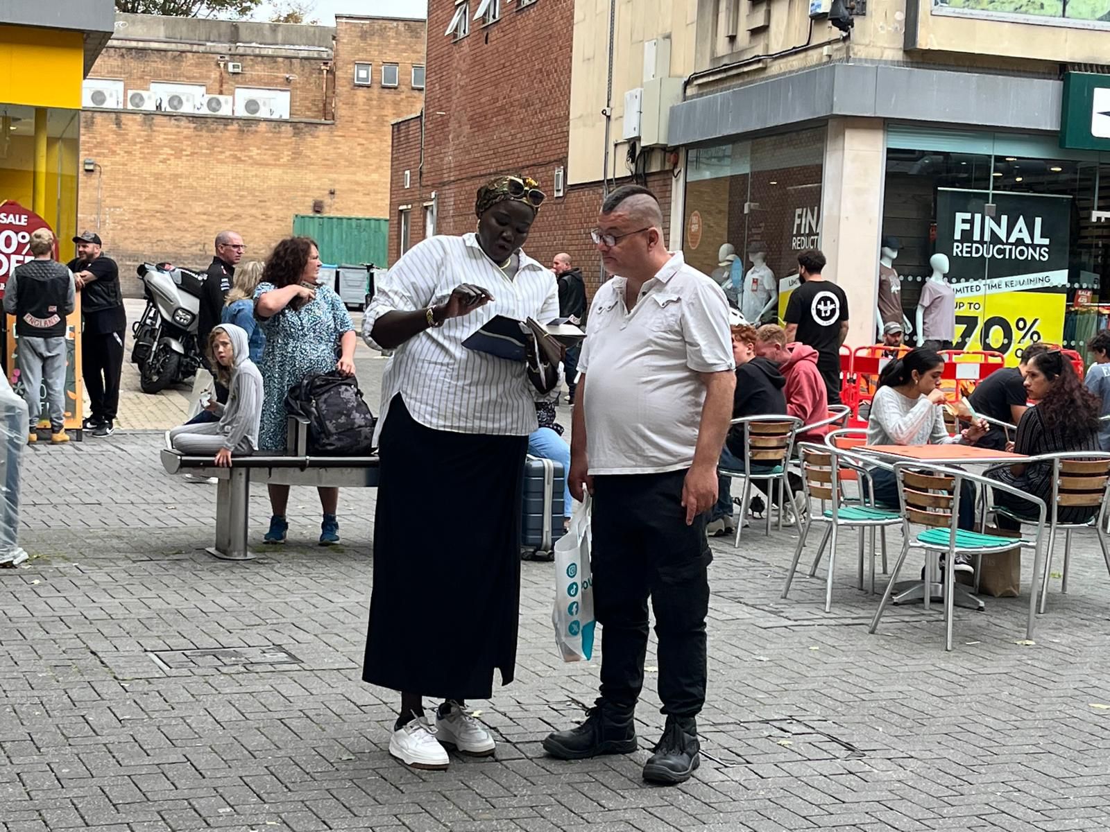 A woman showing a document to a man at a café table